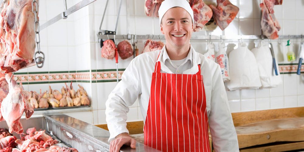 A,Young,Smiling,Butcher,Wearing,A,Red,Apron,Standing,Next
